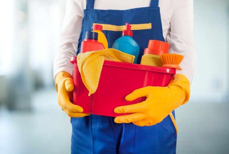 Toowoomba Cleaners staff holding a red bucket full of cleaning products, brushes and cloths