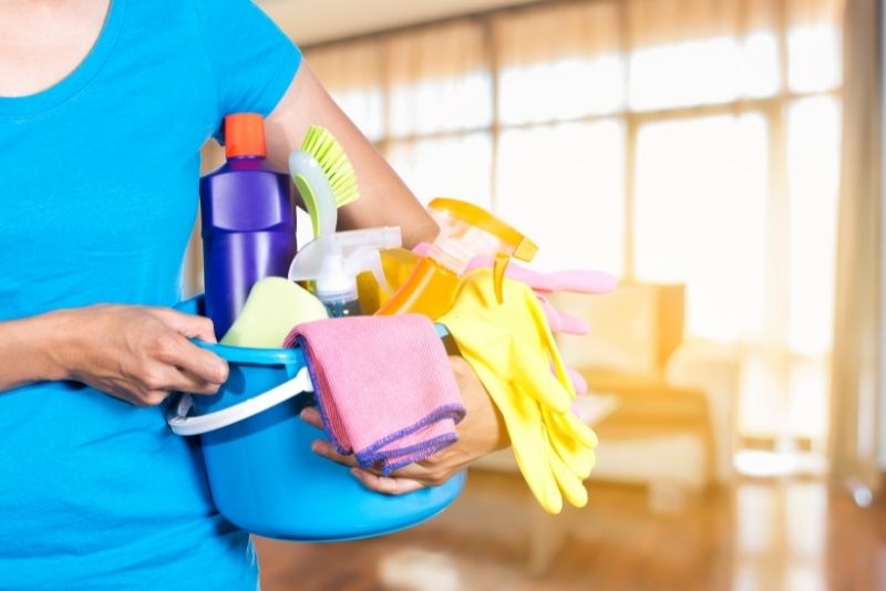 cleaners holding a bucket of various cleaning products
